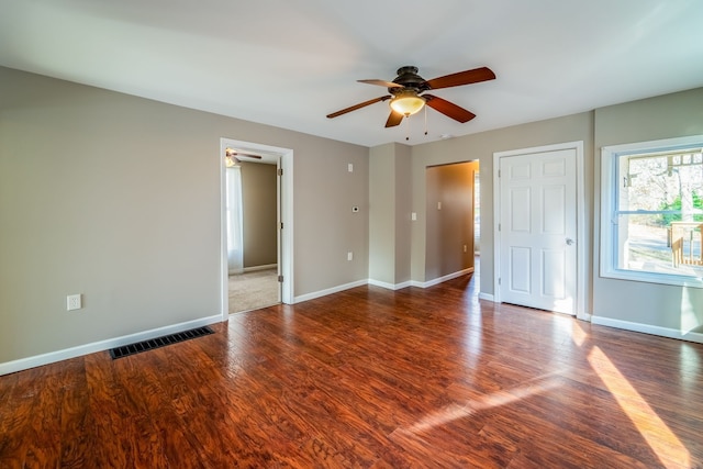 interior space featuring ceiling fan, visible vents, baseboards, and wood finished floors