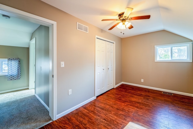 unfurnished bedroom with vaulted ceiling, wood finished floors, visible vents, and baseboards