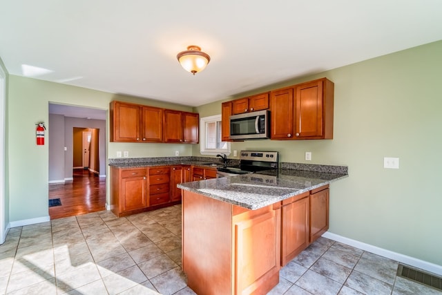 kitchen with visible vents, brown cabinets, appliances with stainless steel finishes, and a peninsula