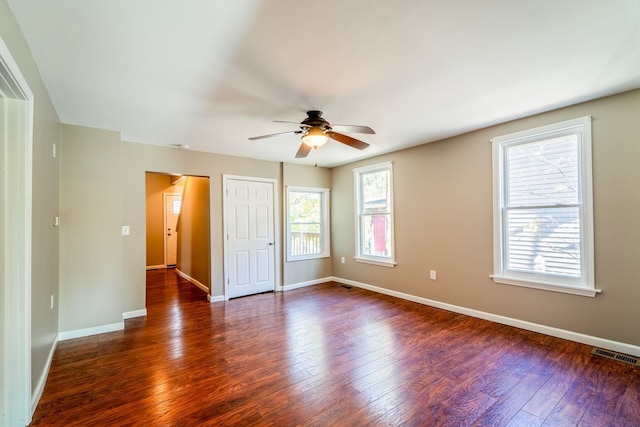 interior space with ceiling fan, visible vents, baseboards, and dark wood finished floors