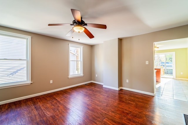 empty room with visible vents, wood finished floors, baseboards, and ceiling fan