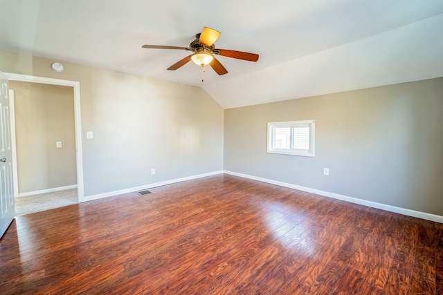 spare room featuring visible vents, baseboards, ceiling fan, vaulted ceiling, and wood finished floors