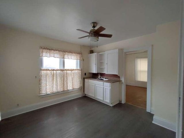 kitchen featuring baseboards, open shelves, a sink, white cabinets, and dark countertops