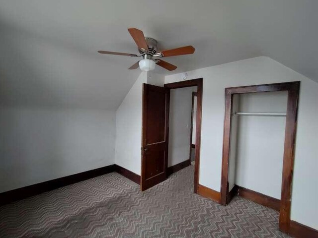 additional living space with a ceiling fan, lofted ceiling, baseboards, and dark colored carpet