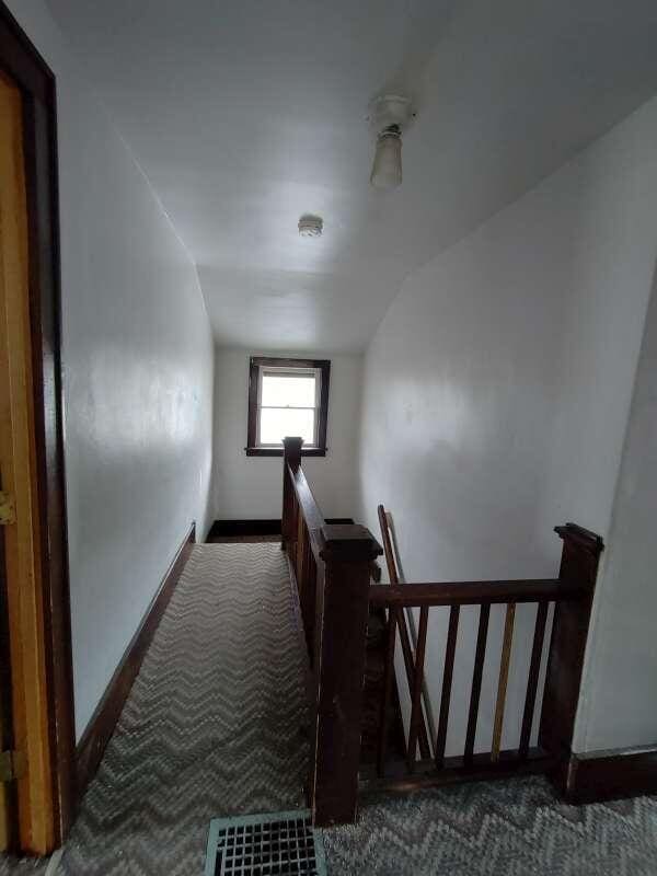 hallway with an upstairs landing, carpet flooring, and baseboards