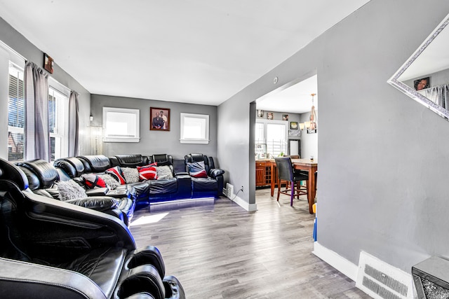living area featuring visible vents, plenty of natural light, baseboards, and wood finished floors