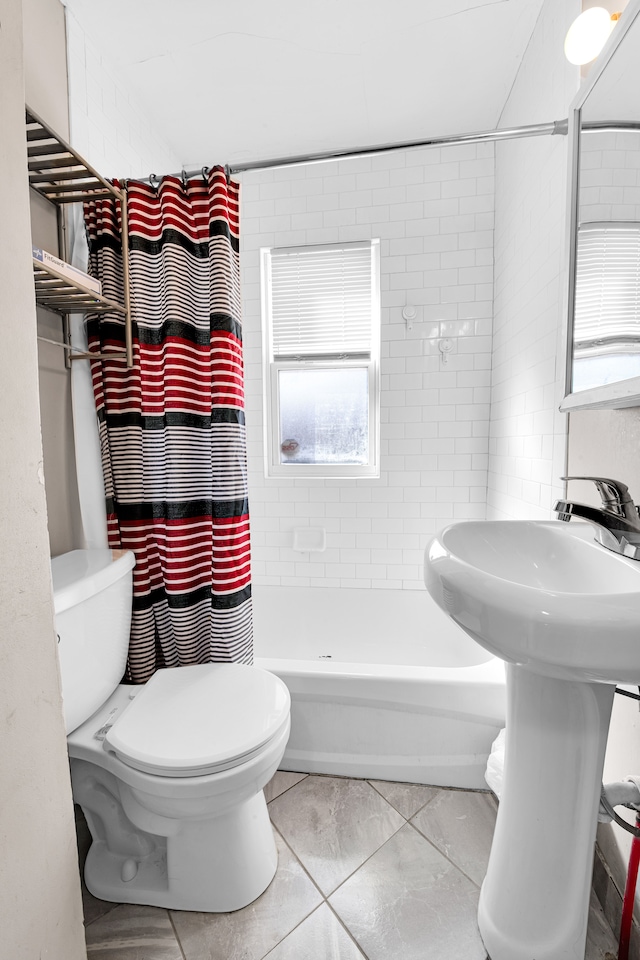 bathroom with toilet, shower / tub combo with curtain, and a sink