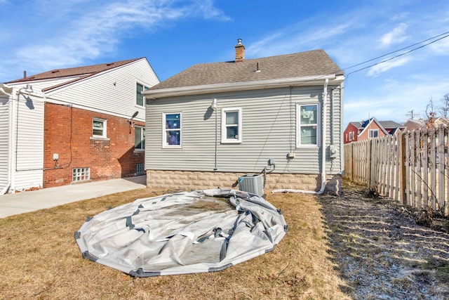 back of property featuring fence, roof with shingles, a yard, a chimney, and a patio area