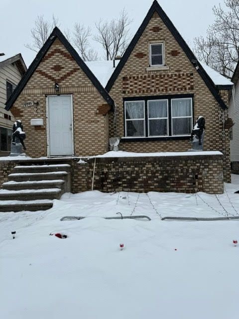 snow covered property with brick siding