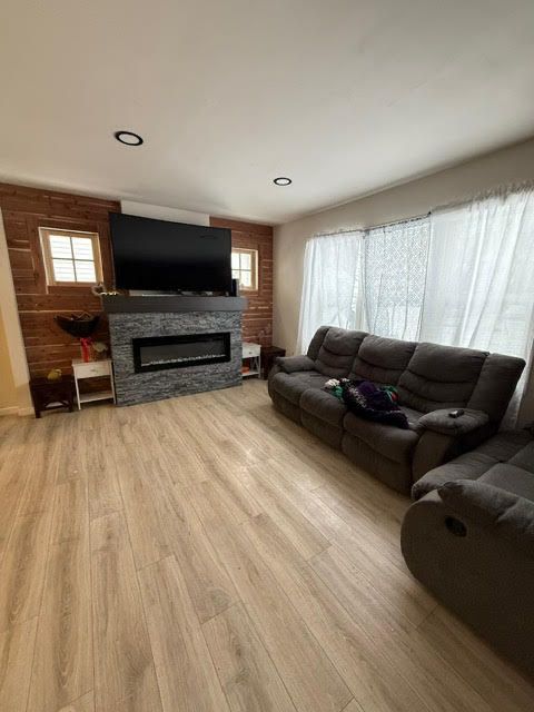 living area with light wood-style flooring, a fireplace, and a healthy amount of sunlight