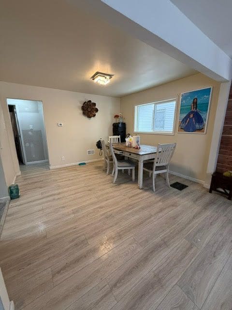 dining space with light wood-style floors, visible vents, and baseboards