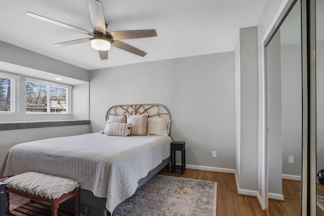 bedroom with a closet, baseboards, wood finished floors, and a ceiling fan