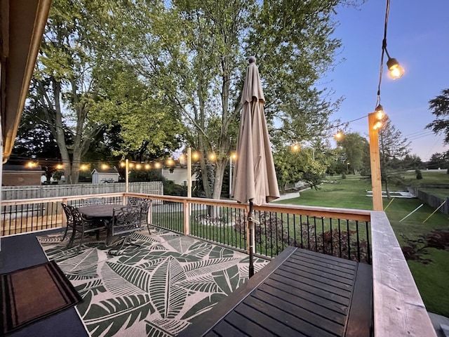 wooden deck featuring outdoor dining area, fence, and a yard