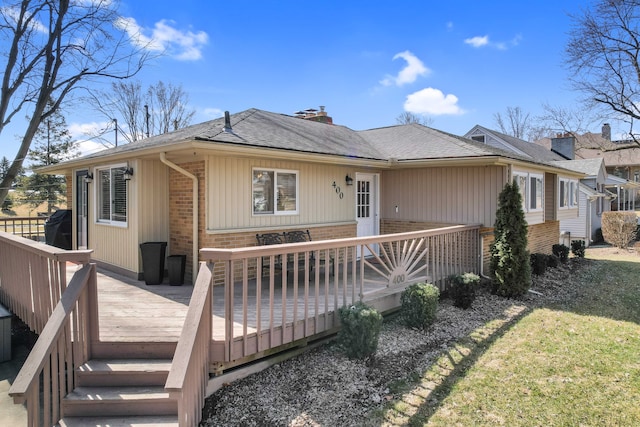 view of front of house featuring a wooden deck, brick siding, a chimney, and a shingled roof