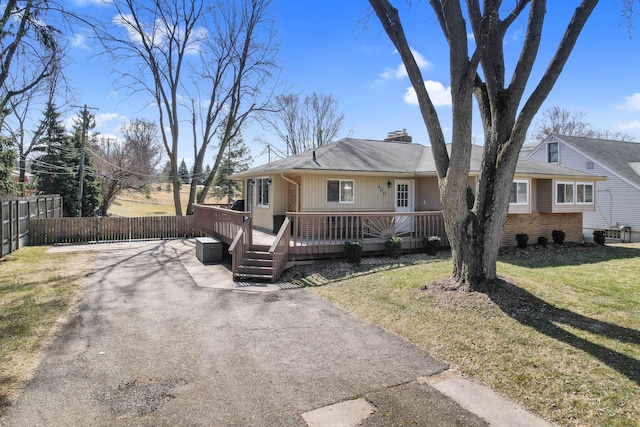 view of front of property with a front lawn, fence, aphalt driveway, a wooden deck, and a chimney