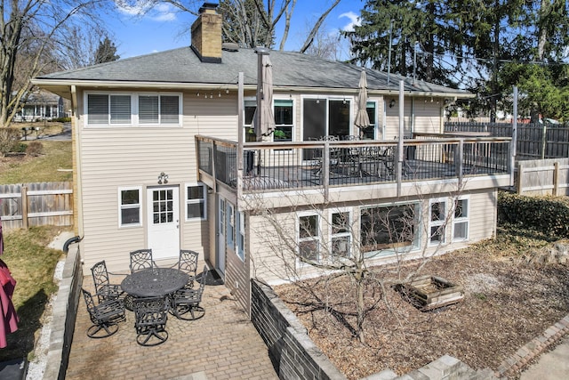 back of property with a patio area, fence, roof with shingles, and a chimney