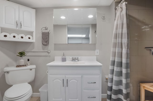 full bath with baseboards, tiled shower, toilet, and vanity