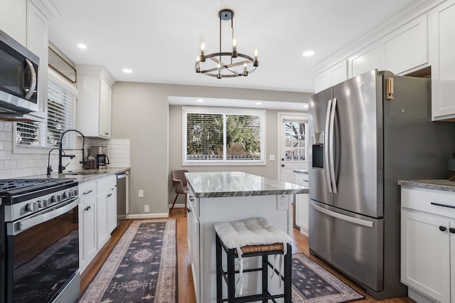 kitchen featuring a healthy amount of sunlight, appliances with stainless steel finishes, a center island, and a sink