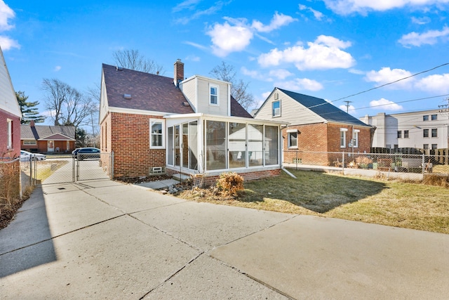 bungalow featuring a gate, fence, a sunroom, a chimney, and brick siding