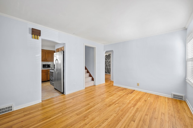 spare room featuring visible vents, light wood finished floors, and stairway