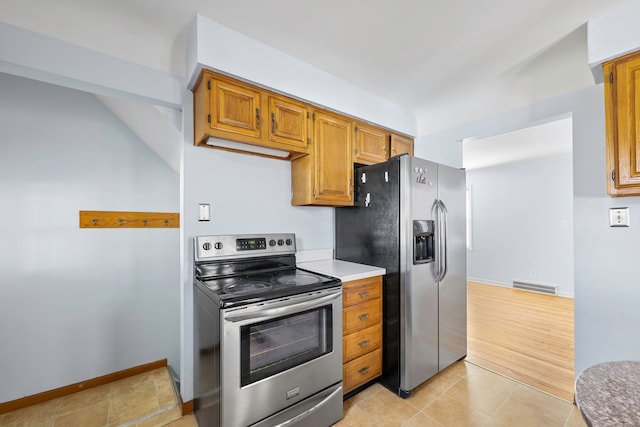 kitchen featuring light tile patterned floors, brown cabinetry, baseboards, visible vents, and appliances with stainless steel finishes