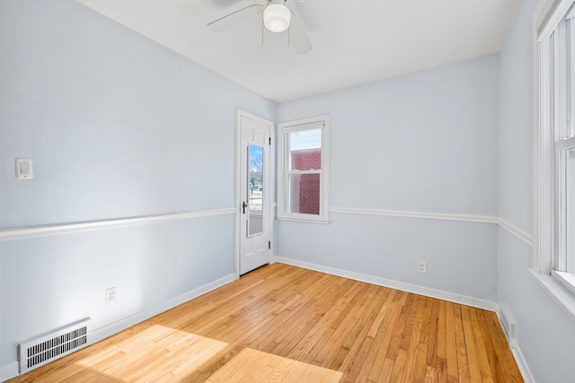 empty room with hardwood / wood-style floors, baseboards, visible vents, and ceiling fan