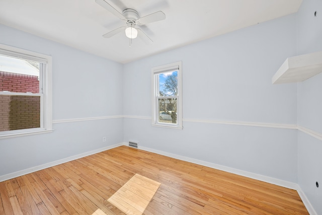 empty room with visible vents, a ceiling fan, baseboards, and wood-type flooring