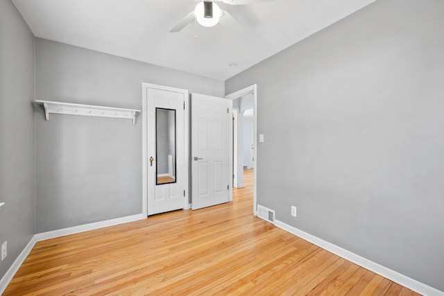 unfurnished bedroom featuring ceiling fan, wood finished floors, visible vents, and baseboards