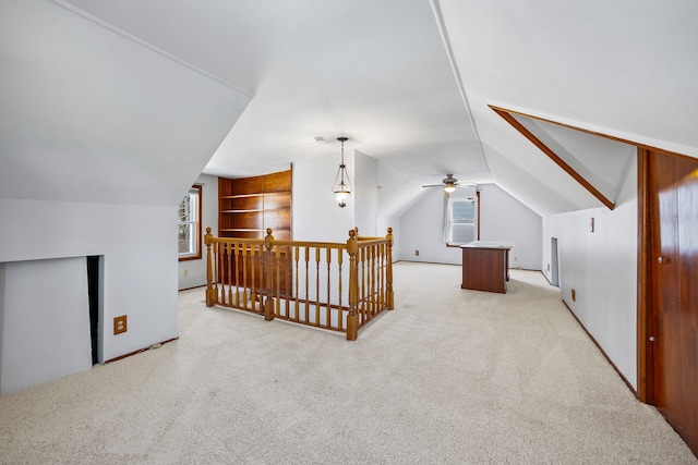 additional living space with a wealth of natural light, light colored carpet, built in shelves, and lofted ceiling