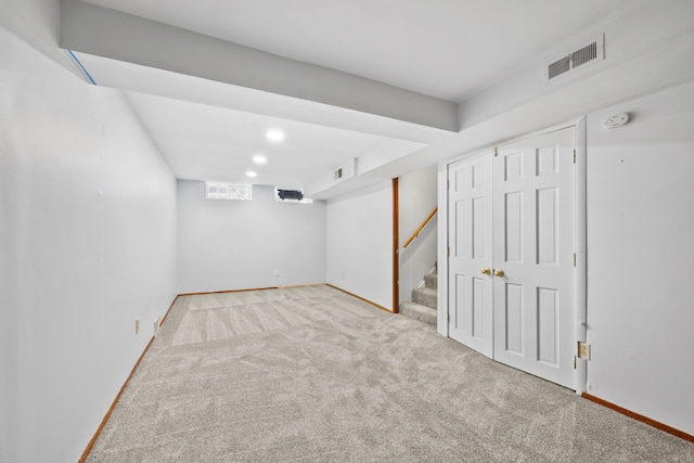 finished below grade area featuring stairway, baseboards, visible vents, and carpet floors