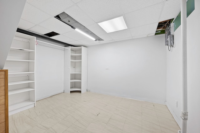 below grade area with tile patterned floors and a paneled ceiling