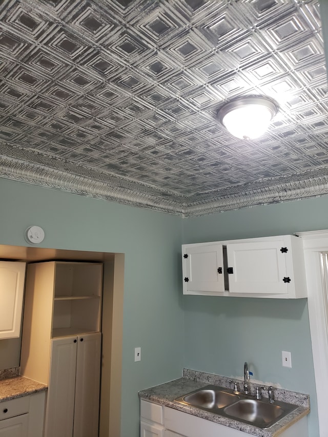 kitchen featuring a sink, an ornate ceiling, and white cabinets