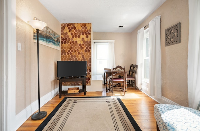 sitting room with wood finished floors, baseboards, and a textured wall