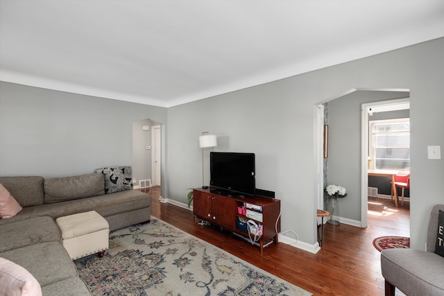 living area featuring visible vents, wood finished floors, and baseboards