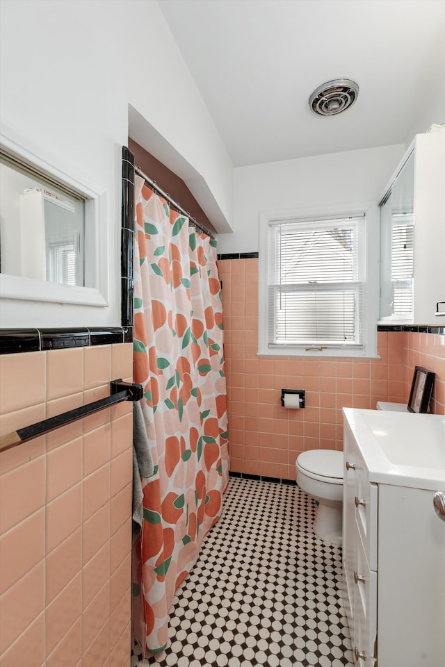 bathroom with vanity, tile walls, toilet, and visible vents