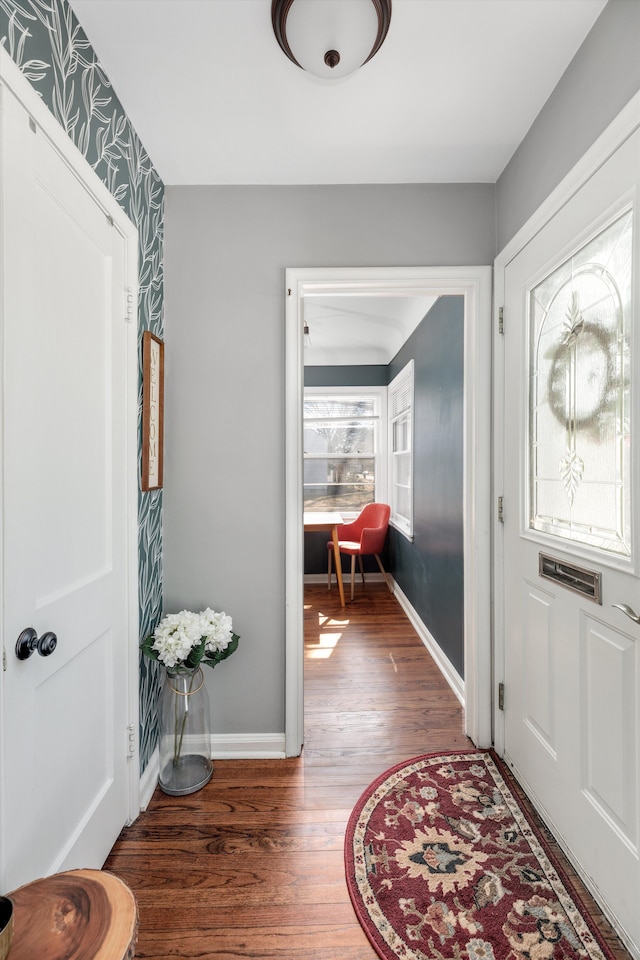 entryway with wallpapered walls, wood finished floors, and baseboards