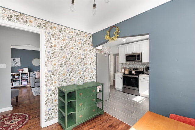 kitchen featuring backsplash, light countertops, appliances with stainless steel finishes, wood finished floors, and white cabinets