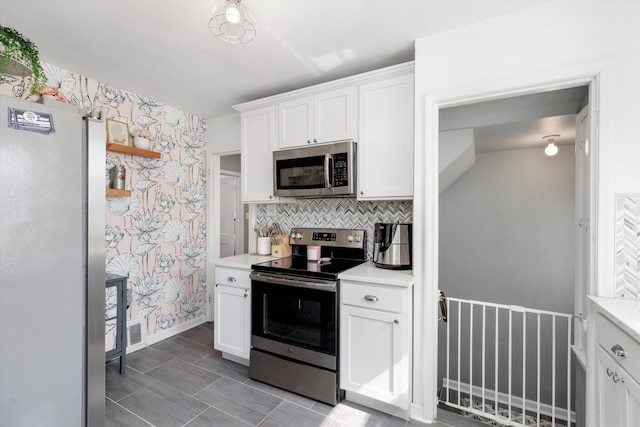 kitchen with stainless steel appliances, white cabinetry, light countertops, and wallpapered walls