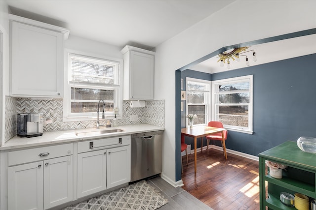 kitchen featuring a sink, tasteful backsplash, wood finished floors, baseboards, and dishwasher