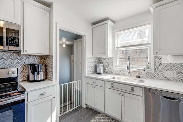 kitchen with a sink, appliances with stainless steel finishes, light countertops, and white cabinetry