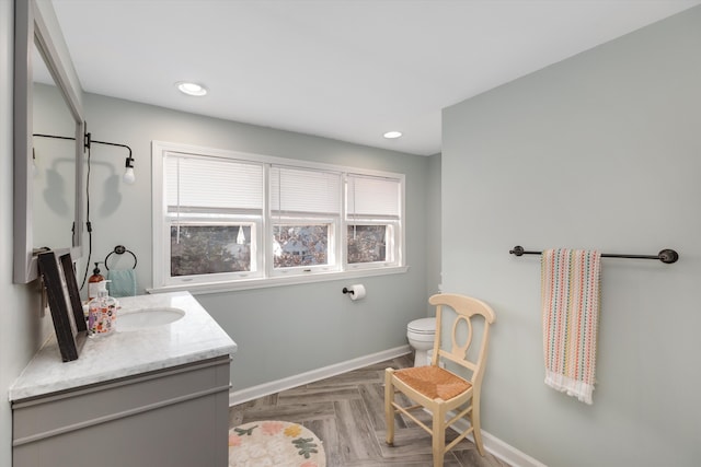 bathroom with recessed lighting, toilet, vanity, and baseboards