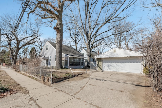 view of front of property with an outbuilding, a detached garage, roof with shingles, and a sunroom