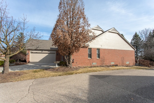 view of side of home with a garage, brick siding, and concrete driveway