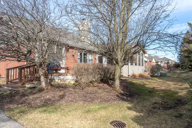 view of side of property featuring a lawn and brick siding