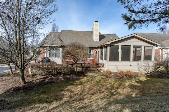 rear view of property with roof with shingles, a yard, a sunroom, a chimney, and brick siding