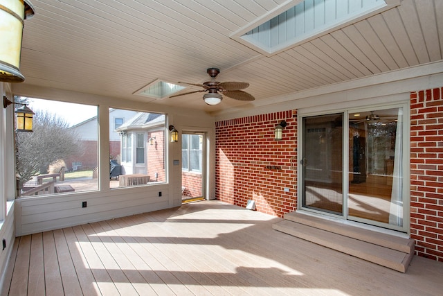 unfurnished sunroom with wooden ceiling, a skylight, and ceiling fan