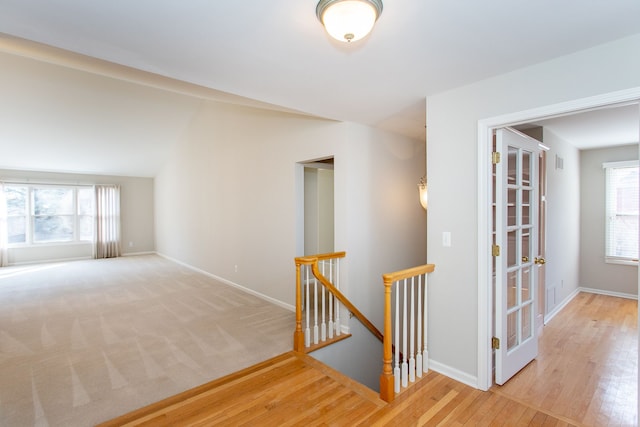 hall featuring baseboards, an upstairs landing, and wood finished floors