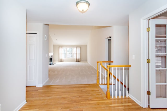 hallway featuring an upstairs landing, light wood-style flooring, and baseboards