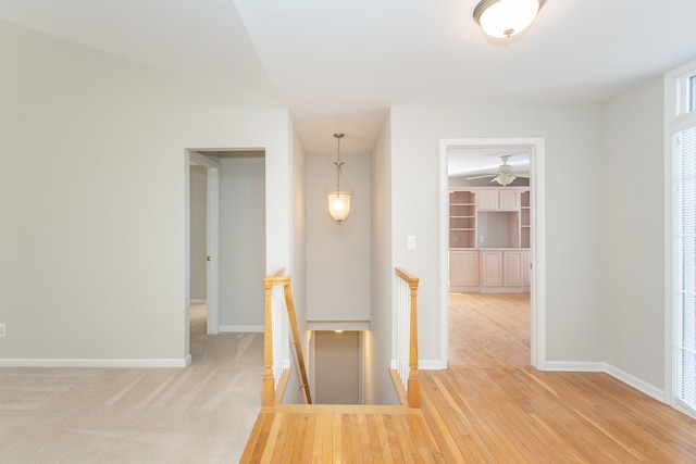 hall featuring baseboards, an upstairs landing, and wood finished floors