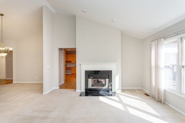 unfurnished living room featuring a fireplace with flush hearth, plenty of natural light, carpet floors, and a chandelier